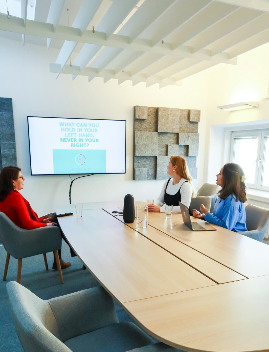 Three women collaborate around a conference table during a training session.